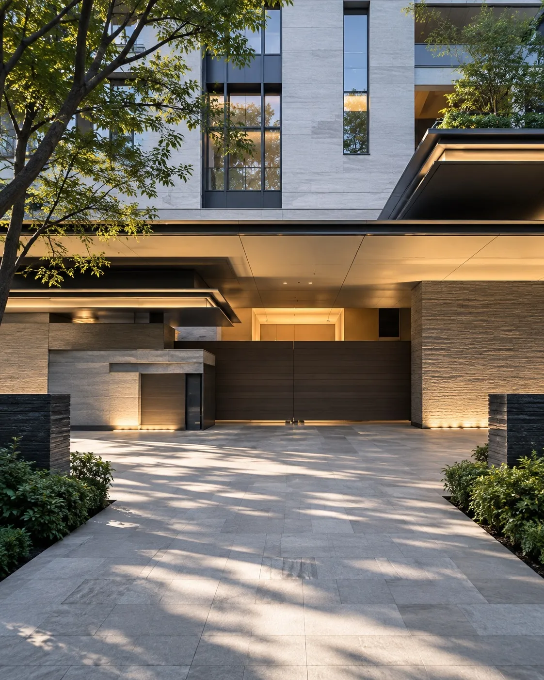 The stone and glass entrance of a contemporary residence in Aoyama, low evening light across a paved forecourt