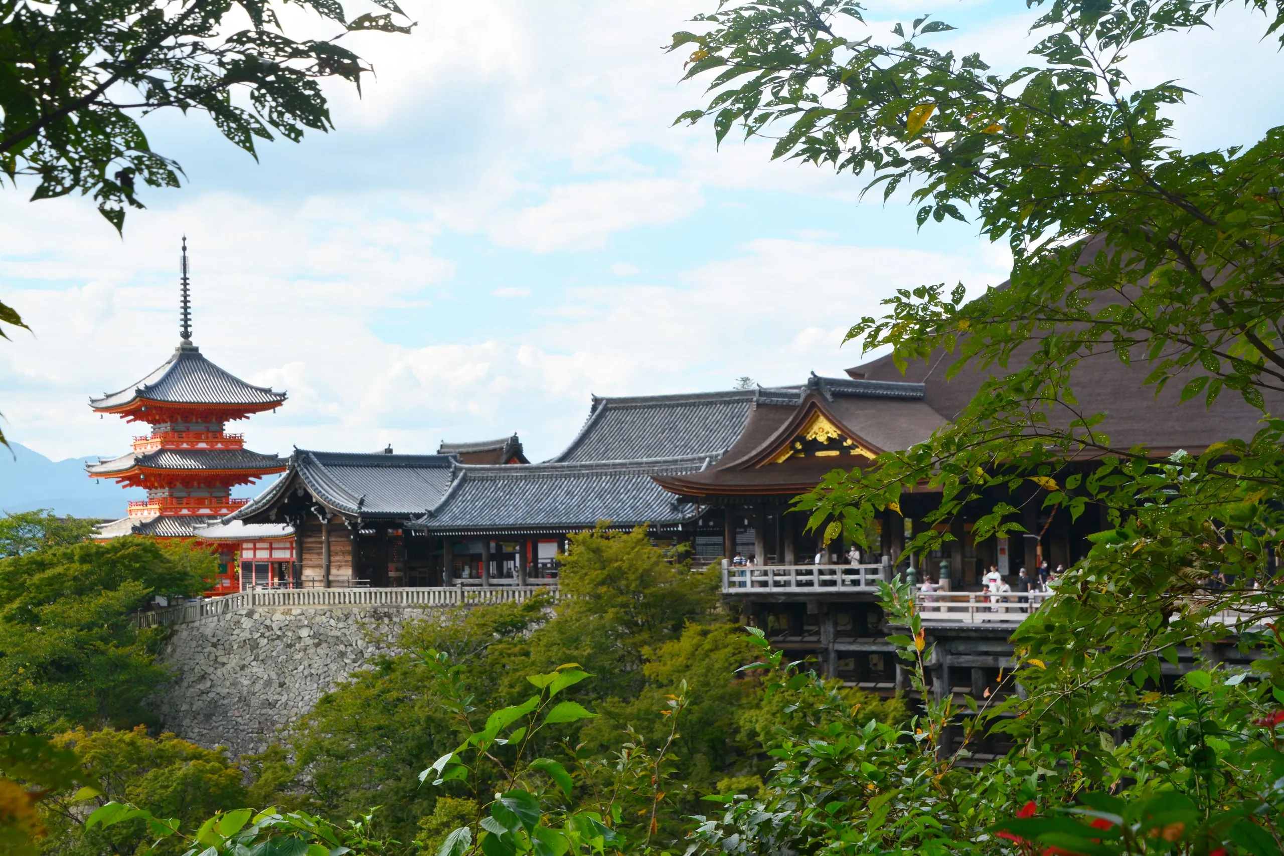 The wooden stage and pagoda of Kiyomizu-dera among green hillside trees in Kyoto